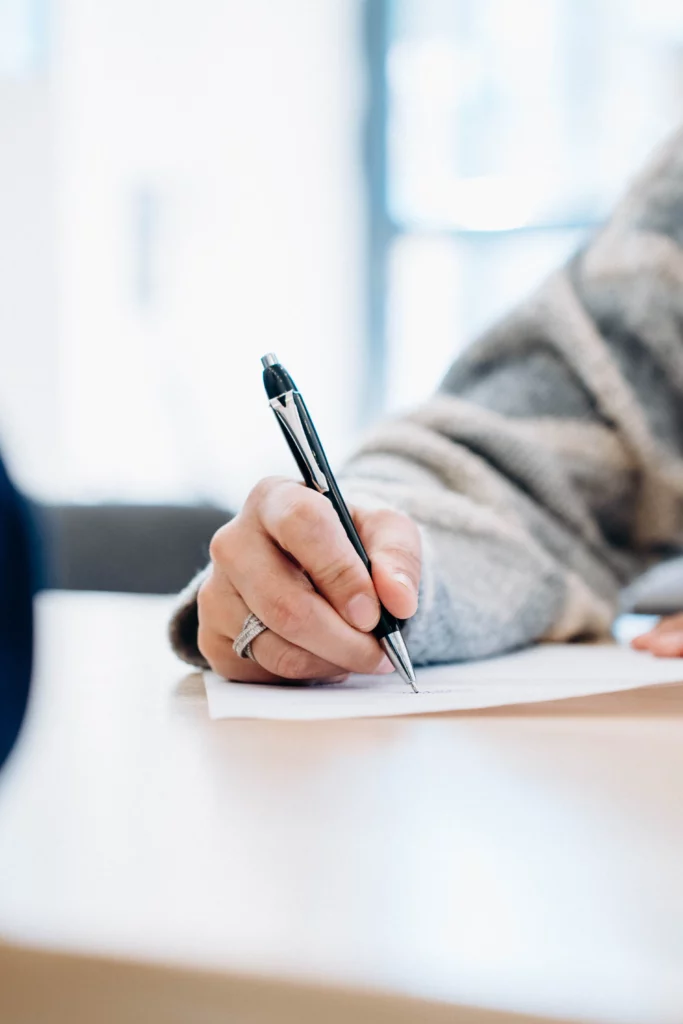 Gros plan sur une main signant un contrat immobilier avec un stylo, représentant l'achat ou la vente d'un bien.